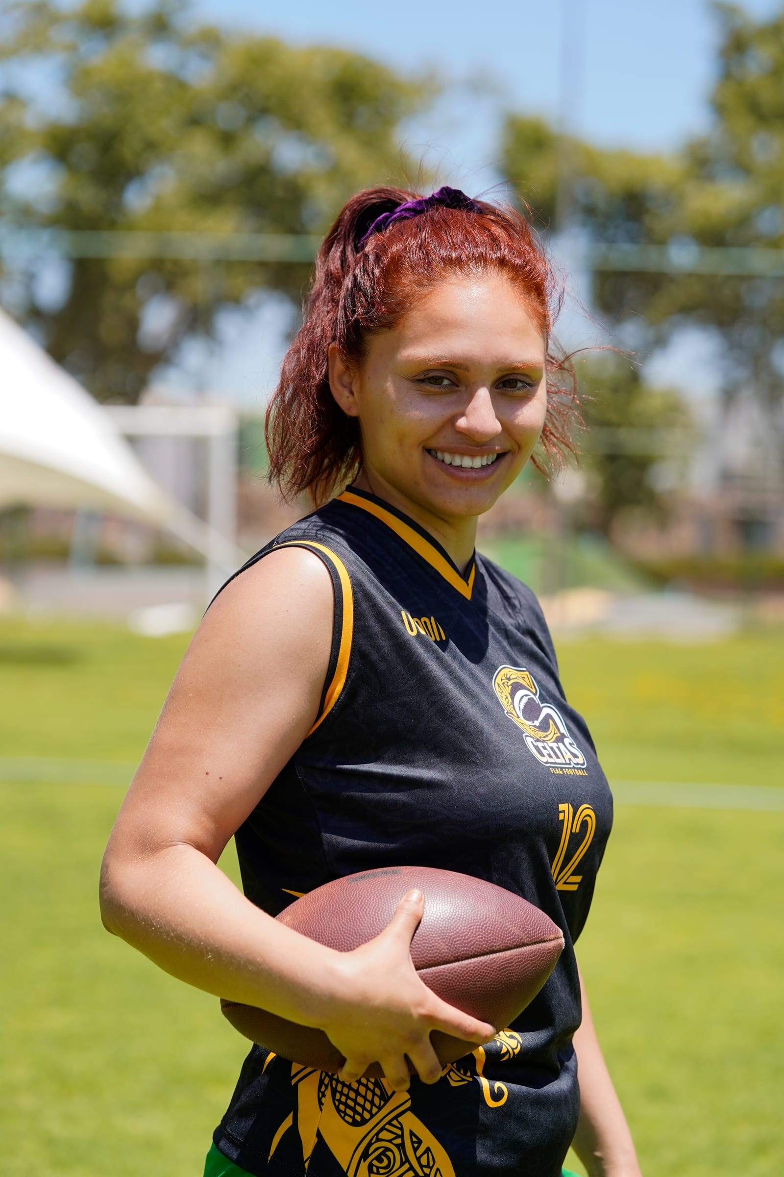 Jugadora de flag football sonriendo con el balón